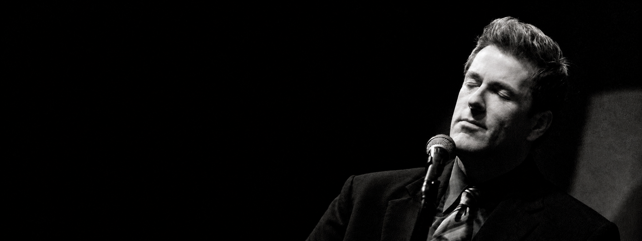 Russ Lorenson singing into a microphone, in black and white.